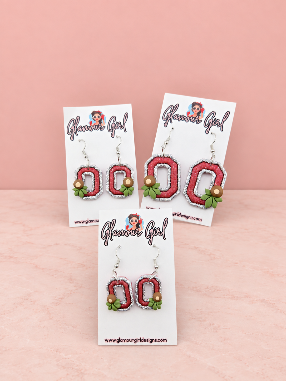 Scarlet Buckeye Block O earrings group view on blush pink background