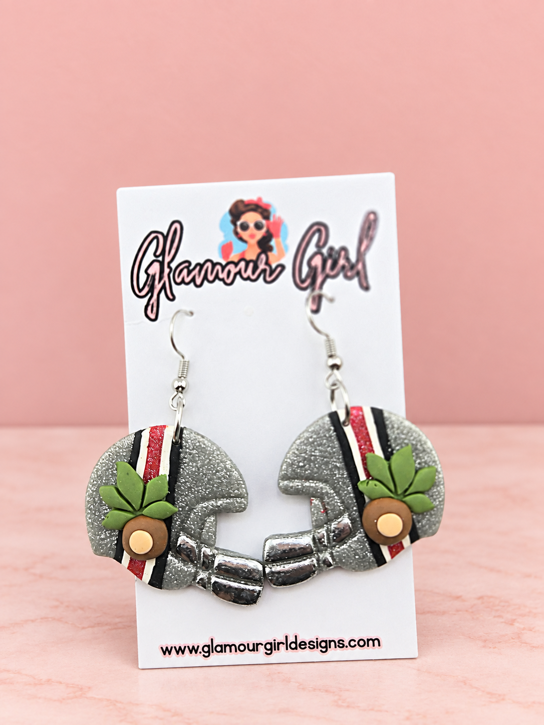 Buckeye helmet earrings distance view on blush pink background
