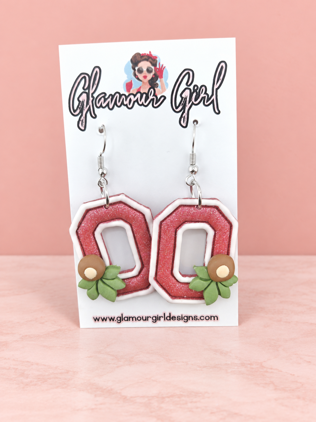 Scarlet Buckeye Block O earrings distance view on blush pink background