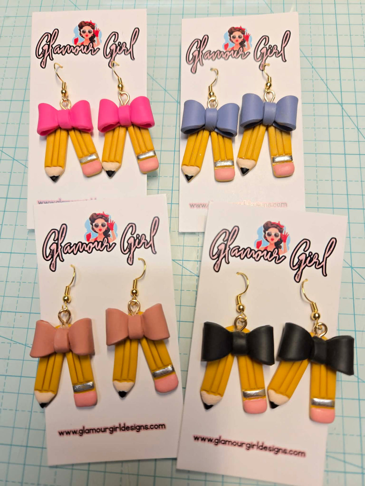 Original photo of yellow pencil dangle earrings with Hot Pink, Periwinkle, Peach and Black bows on Glamour Girl display cards.